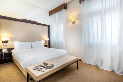 a bedroom with a large white bed and a table at Europalace Hotel, BW Signature Collection in Monfalcone