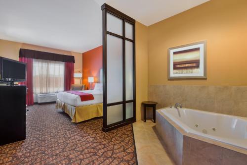 a hotel room with a bed and a bath tub at Holiday Inn Express and Suites Alpine by IHG in Alpine
