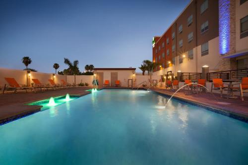 a swimming pool in front of a hotel at night at Holiday Inn Express & Suites - McAllen - Medical Center Area by IHG in McAllen