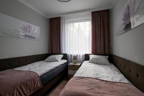 dwa łóżka w pokoju z oknem w obiekcie Apartament Leśny No 4 Blue w Kielcach