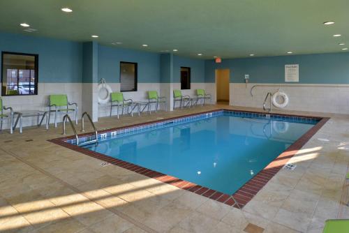 a pool in a hotel room with chairs and tables at Holiday Inn Express Hotel & Suites Lonoke I-40 by IHG in Lonoke