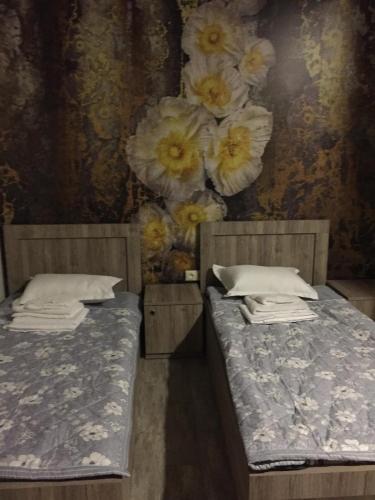two beds in a room with flowers on the wall at Nimako's Apartment in Borjomi