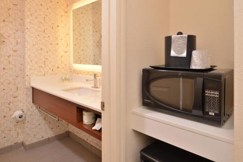 a bathroom with a microwave and a sink at Holiday Inn & Suites Raleigh Cary, an IHG Hotel in Cary