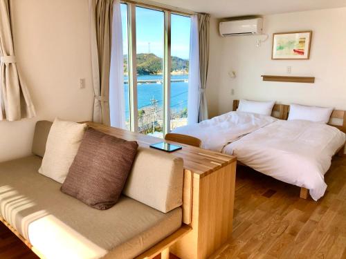 直島町にあるMY LODGE Naoshimaのソファと窓が備わる客室内のベッド2台