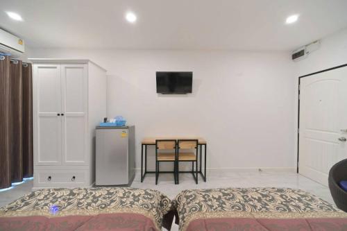 a room with two beds and a table with a tv at Parvena Ratchada in Bangkok