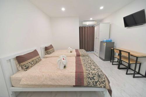 a bedroom with two beds and a table and a television at Parvena Ratchada in Bangkok