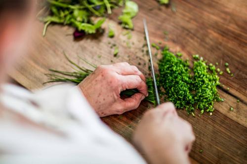 a person cutting up broccoli on a table with a knife at Hotel Tann in Collalbo