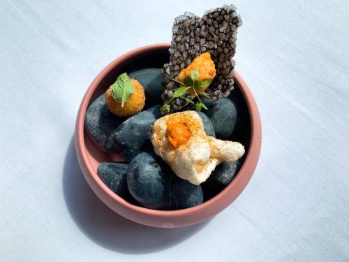 a red bowl filled with rocks and food on a table at Volando Urai Spring Spa & Resort in Wulai