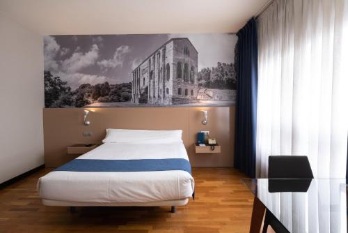 1 dormitorio con 1 cama y una foto de un edificio en Aparthotel Campus, en Oviedo