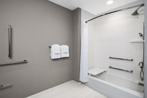 Holiday Inn Express & Suites Lubbock Central - Univ Area, an IHG Hotel في لوبوك: حمام أبيض مع حوض استحمام ودش