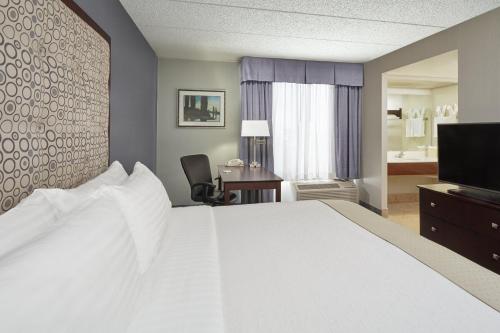 a hotel room with a bed and a desk and a television at Holiday Inn & Suites Chicago-Carol Stream Wheaton by IHG in Carol Stream