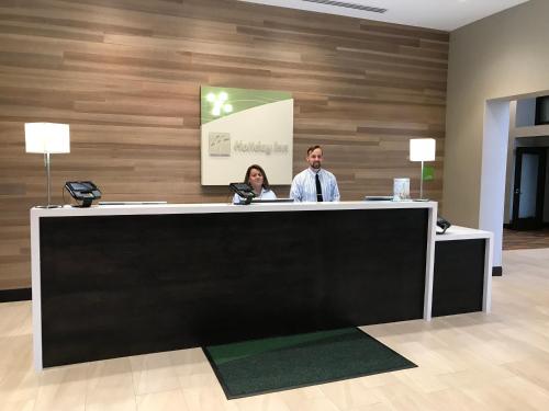 a man and a woman standing at a reception desk at Holiday Inn & Suites Chicago-Carol Stream Wheaton by IHG in Carol Stream