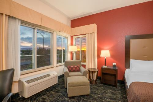 a hotel room with a bed and a chair and windows at Holiday Inn Hotel & Suites Grand Junction-Airport by IHG in Grand Junction
