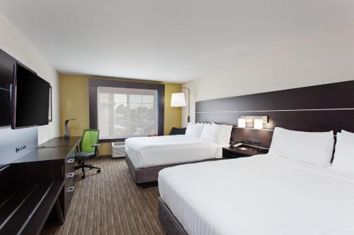 オークランドにあるHoliday Inn Express & Suites Oakland - Airport, an IHG Hotelのベッド2台、薄型テレビが備わるホテルルームです。