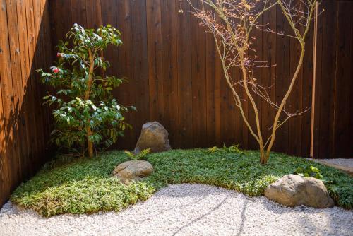 a garden with a tree and rocks in front of a fence at Shiki Homes TSURU KAME in Kyoto