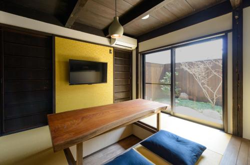a room with a bench and a tv and a window at Shiki Homes TSURU KAME in Kyoto