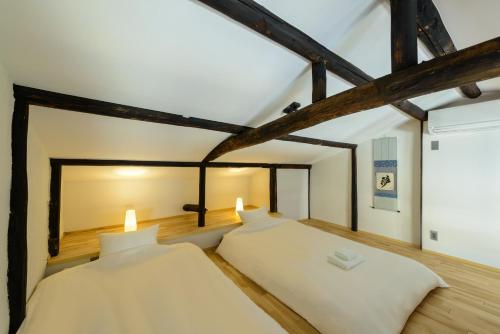 two beds in a room with exposed beams at Shiki Homes TSURU KAME in Kyoto