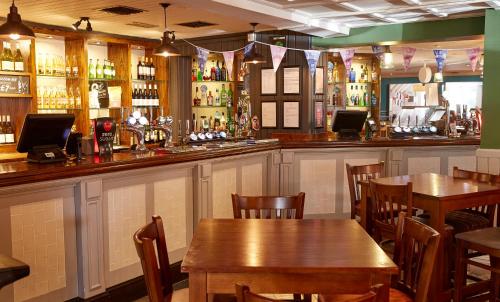 a bar with wooden tables and chairs in a restaurant at Darrington by Greene King Inns in Darrington