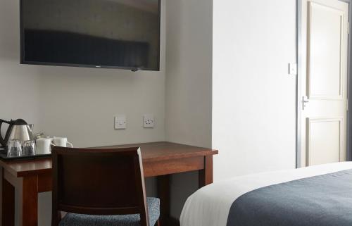 a bedroom with a desk with a bed and a television at Darrington by Greene King Inns in Darrington