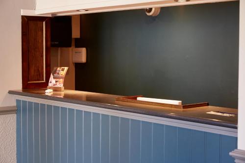 a counter with a blue wall and a mirror at Darrington by Greene King Inns in Darrington