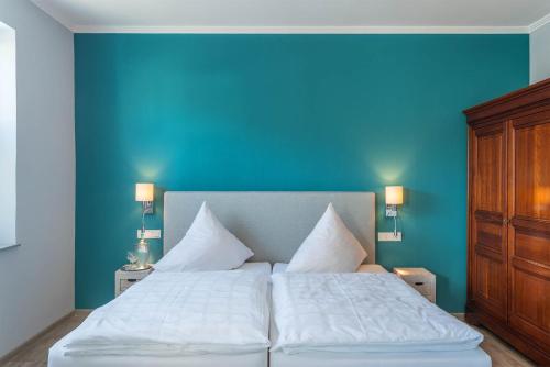 a bedroom with a large white bed with a blue wall at Hotel Koch Schilt in Irrel