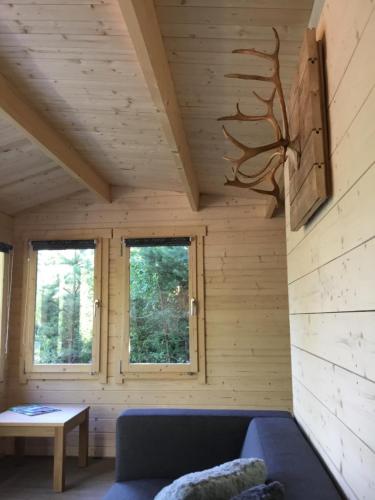 a living room with a blue couch and two windows at Cozy Lodge near Brattforsheden nature reserve in Filipstad