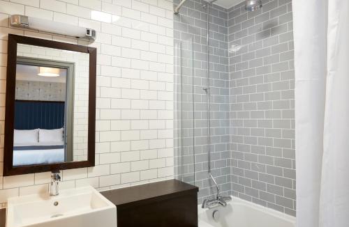 a bathroom with a sink and a mirror and a tub at Darrington by Greene King Inns in Darrington