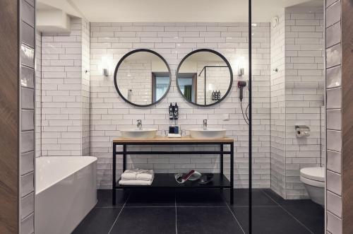 a bathroom with two sinks and two mirrors at Carlton President in Utrecht
