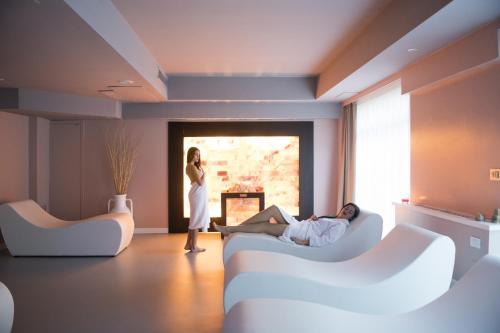 a woman standing in a living room with a man laying on a couch at Regiohotel Manfredi in Manfredonia