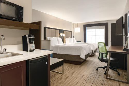 a hotel room with a bed and a kitchen with a sink at Holiday Inn Express Hotel & Suites Lawton-Fort Sill by IHG in Lawton