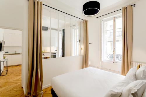 une chambre avec un lit blanc et une grande fenêtre dans l'établissement Habitat Parisien - 1BR-1BA - Louvre, à Paris