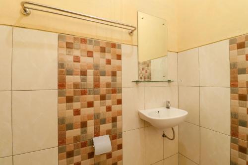 een badkamer met een wastafel en een spiegel bij The Joglo Family Hotel in Magelang