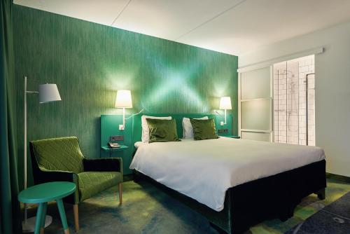 a hotel room with a bed, chair, and nightstand at Carlton President in Utrecht