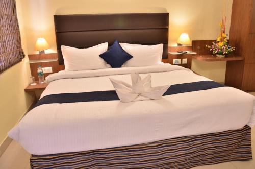 a bedroom with a large bed with white sheets and blue pillows at LBD RESORTS & HOTELS KOLKATA in Kolkata