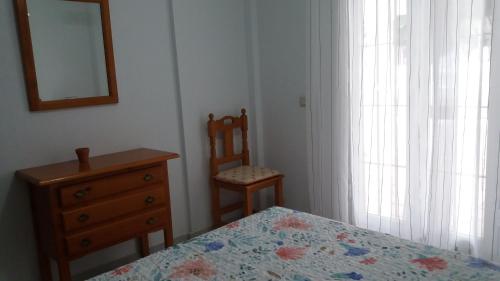 1 dormitorio con cama, tocador y espejo en Playa de La Barrosa La Almadraba IV Fase "Interior" B-3, en Chiclana de la Frontera