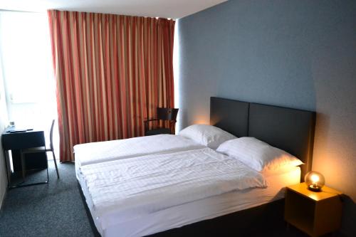 a bedroom with a large white bed and a window at Hotel Les Rives Du Doubs in Les Brenets