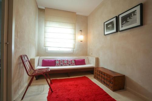 a room with a white couch and a red rug at Apartamentos Caravane in Tarifa
