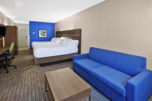 a hotel room with a bed and a blue couch at Holiday Inn Express Hotel & Suites Manchester Conference Center by IHG in Manchester