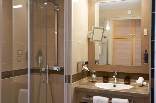 a bathroom with a sink and a shower with a mirror at Hotel Vatel Bordeaux in Bordeaux