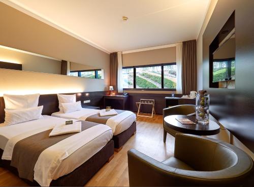 een hotelkamer met 2 bedden en een bank bij d'Coque Hotel in Luxemburg