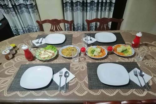 a table with white plates and bowls of food at Airport A4 Transit Hub - Eco Chalets in Katunayake