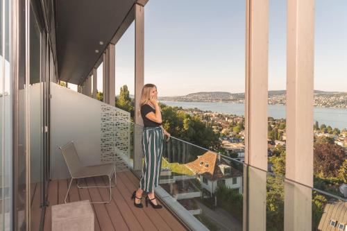 a woman and a man sitting on a balcony overlooking the ocean at Belvoir Swiss Quality Hotel in Rüschlikon