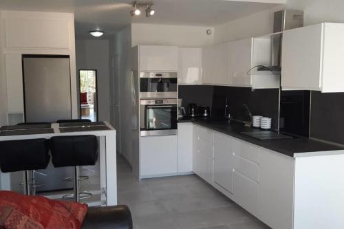 une cuisine avec des armoires blanches et des comptoirs noirs dans l'établissement Naturiste Cap d'Agde Villa Héliovillage 3, au Cap d'Agde