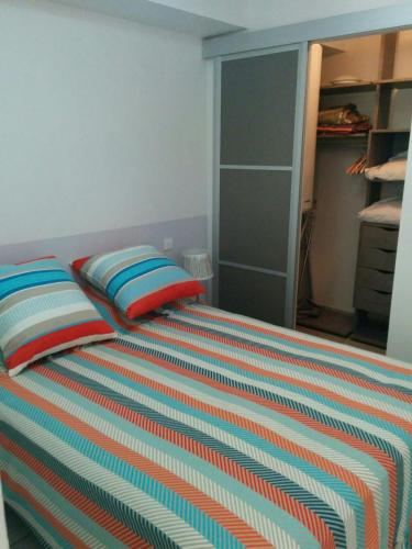 een slaapkamer met een bed met een kleurrijk gestreepte deken bij Cap d 'Agde Naturist Port Nature 8 in Cap d'Agde