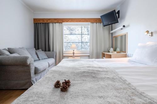 a bedroom with a large white bed and a couch at Lapland Hotels Bear´s Lodge in Sinettä