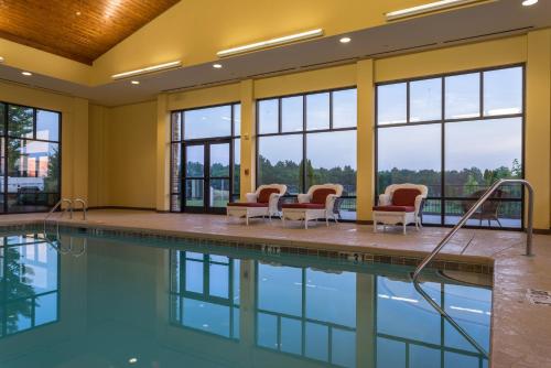 a swimming pool with chairs and a table and windows at Holiday Inn Express & Suites Lexington North West-The Vineyard by IHG in Lexington