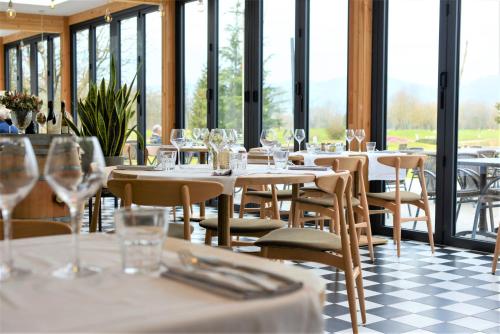 a restaurant with white tables and chairs and windows at Domaine de Charmeil in Saint-Quentin-sur-Isère