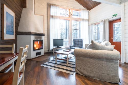 sala de estar con sofá y chimenea en Lapland Hotels Bear´s Lodge en Sinettä