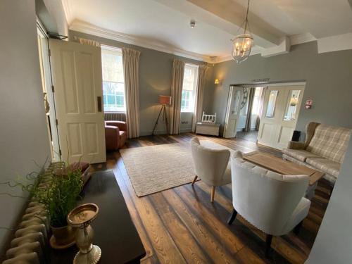 uma sala de estar com um sofá, uma mesa e cadeiras em Kedleston Country House B&B em Derby