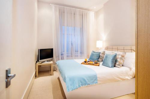 a bedroom with a bed with a tray of food on it at All2Stay South Kensington Apartment in London